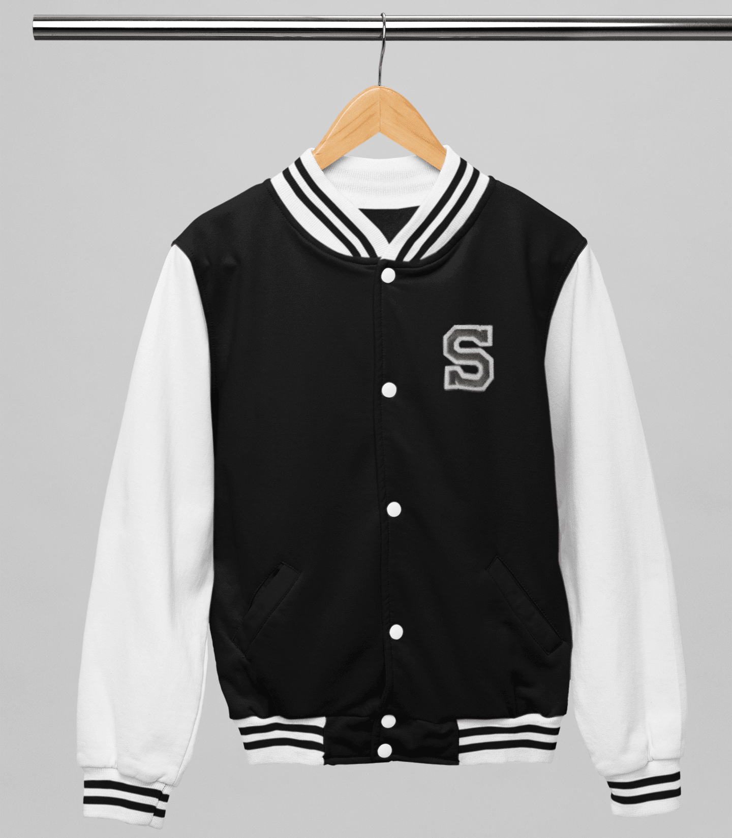 Black and white varsity jacket with a letter 'S' on a hanger against a gray background